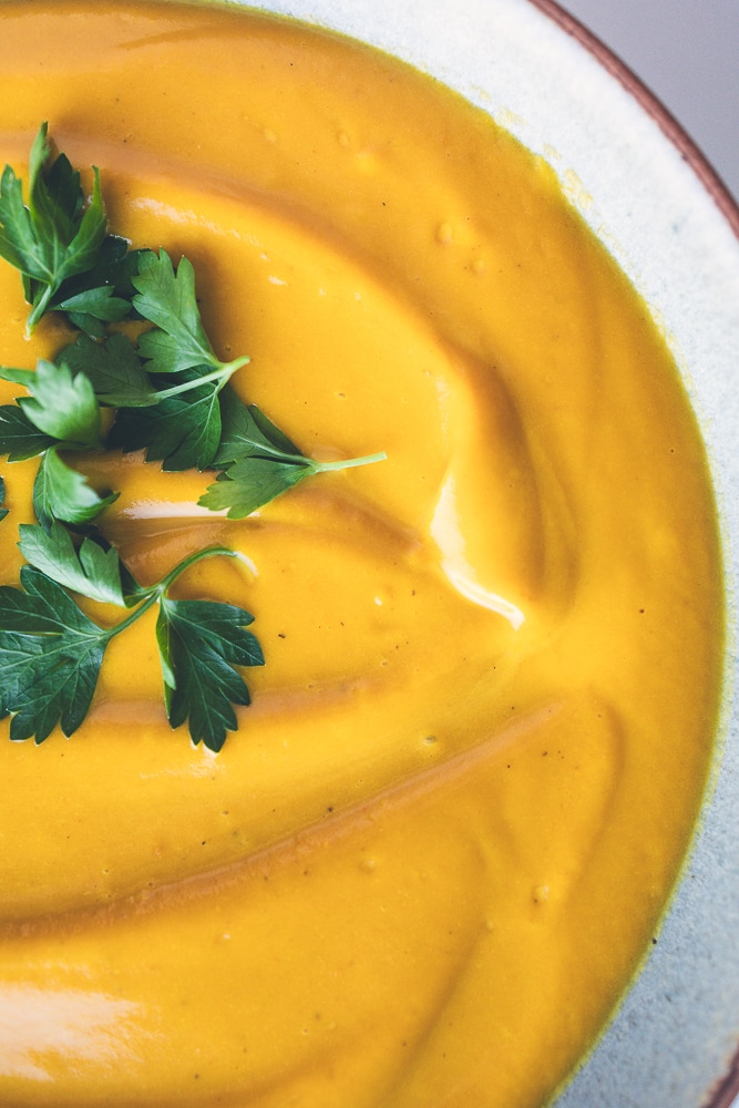 Golden roasted sweet potato soup topped with fresh parsley